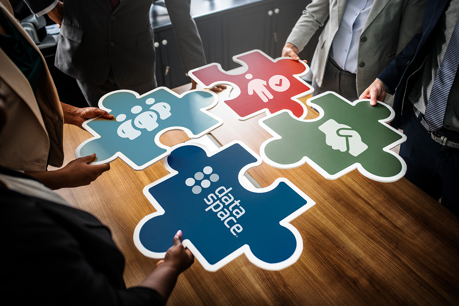 An image of four business people holding large puzzle pieces that fit together.